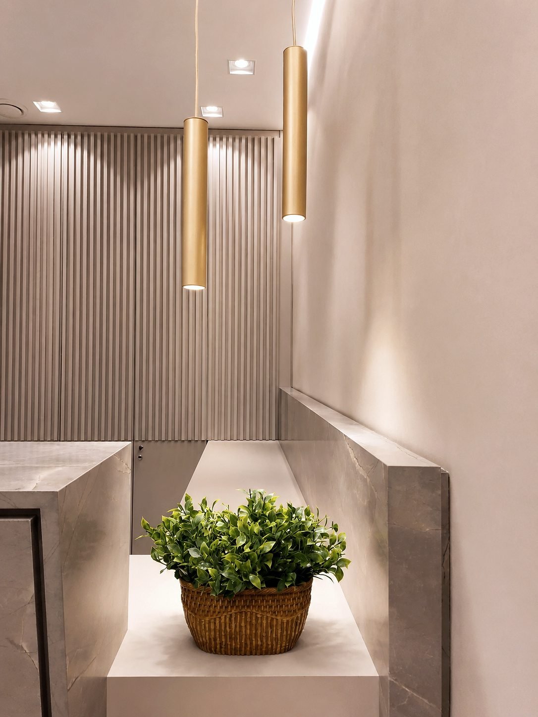 Detalhe da recepção da Specialittá com painel ripado, luminárias pendentes e porcelanato